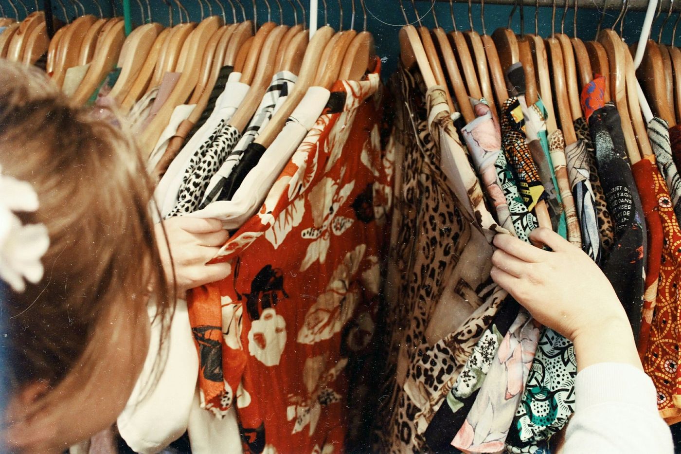 Hands browsing a rack of patterned vintage garments